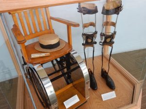 FDR's wheelchair and braces are on display. in a museum case.