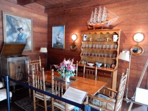 Interior of a dining room with wooden walls with a sailboat displayed on a cabinet hutch.