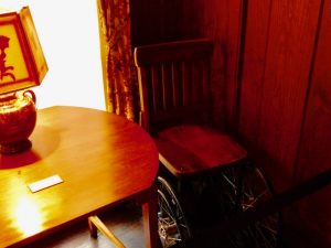 FDR's wheelchair next to a table and lamp.